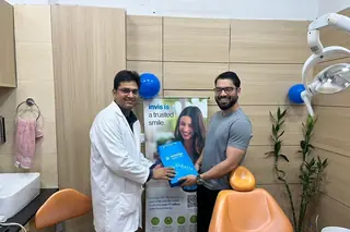 Dr. Naveen Yadav with Invisalign patient holding aligner bag at Root Care Dental Clinic, Gurugram