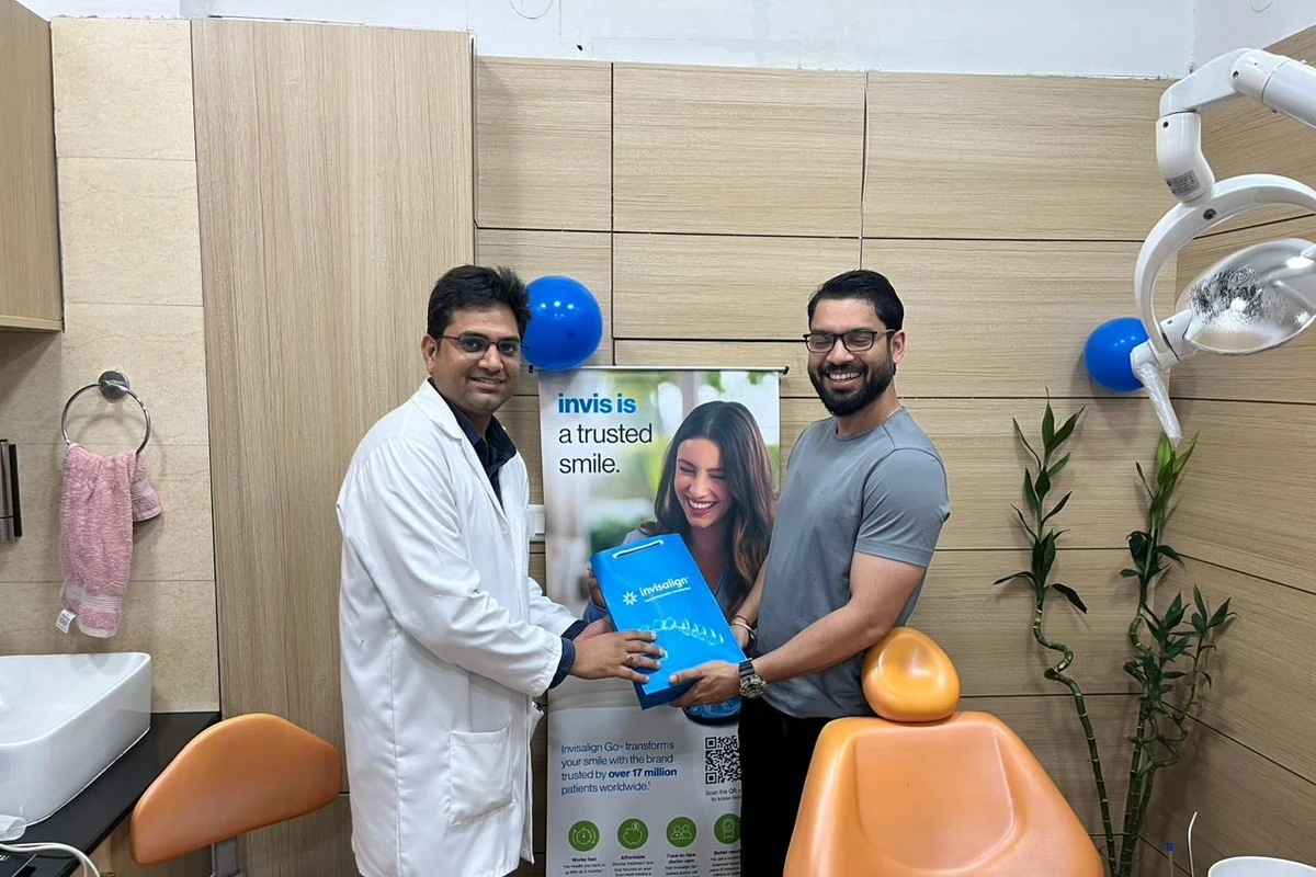 Dr. Naveen Yadav with Invisalign patient holding aligner bag at Root Care Dental Clinic, Gurugram